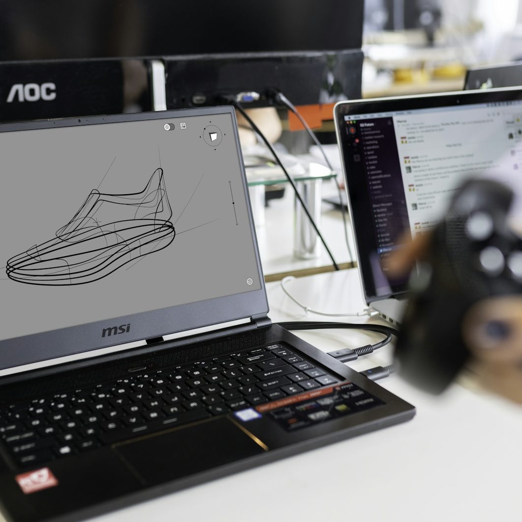 3d Design und Druck Entwurf eines Sportschuhs auf einem Laptop-Bildschirm, daneben ein weiterer Laptop.